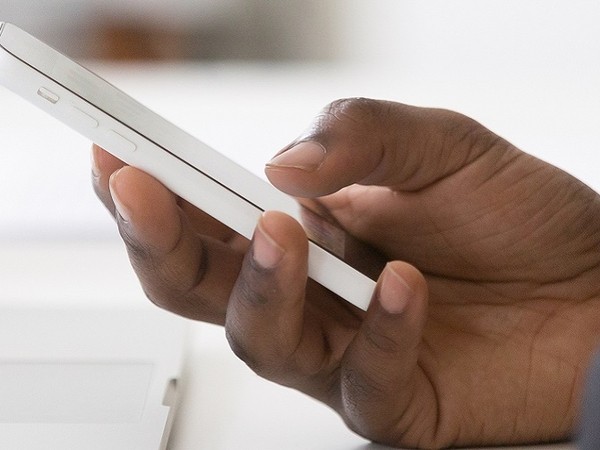 Close-up of a hand holding and using a white smartphone with a blurred background.