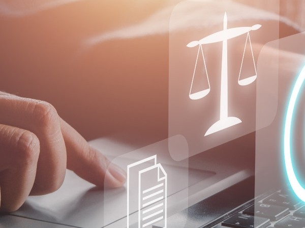 Close-up of a hand using a laptop touchpad with translucent digital icons of a document and a justice scale overlayed, suggesting legal or document-related technology.