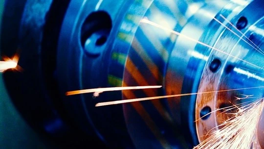 Close-up of sparks flying from a metal grinding or cutting machine in an industrial setting