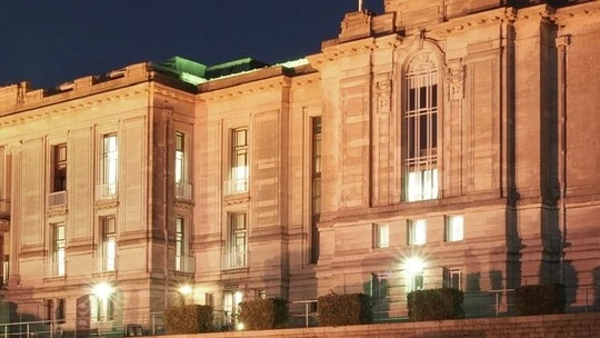 Illuminated historic building facade at night with tall windows and stone architectural details