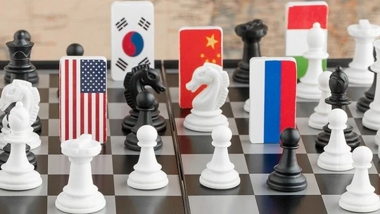 Chessboard with white and black chess pieces interspersed with rectangular blocks featuring flags of various countries including the United States, South Korea, China, Russia, and others, symbolizing an international chess game or geopolitical strategy.