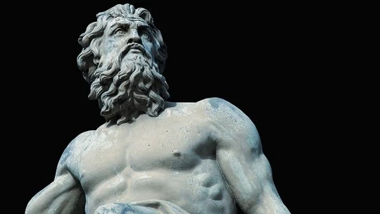 Marble statue of a muscular bearded man with flowing hair, gazing upward against a black background